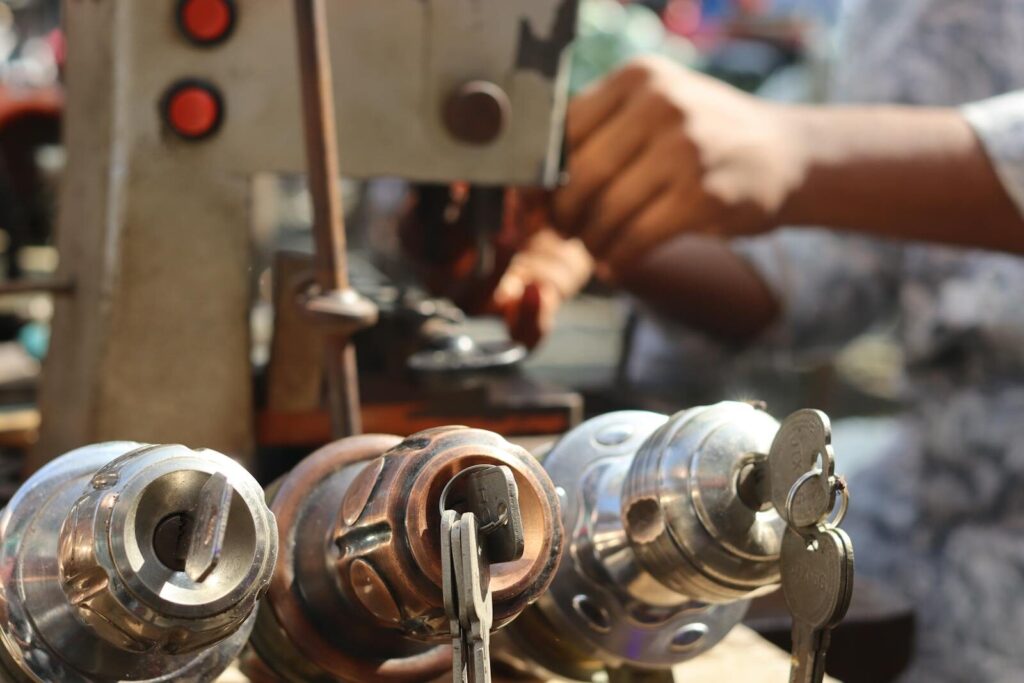 Close-up image of locksmith tools and hands working with a key machine outdoors.
